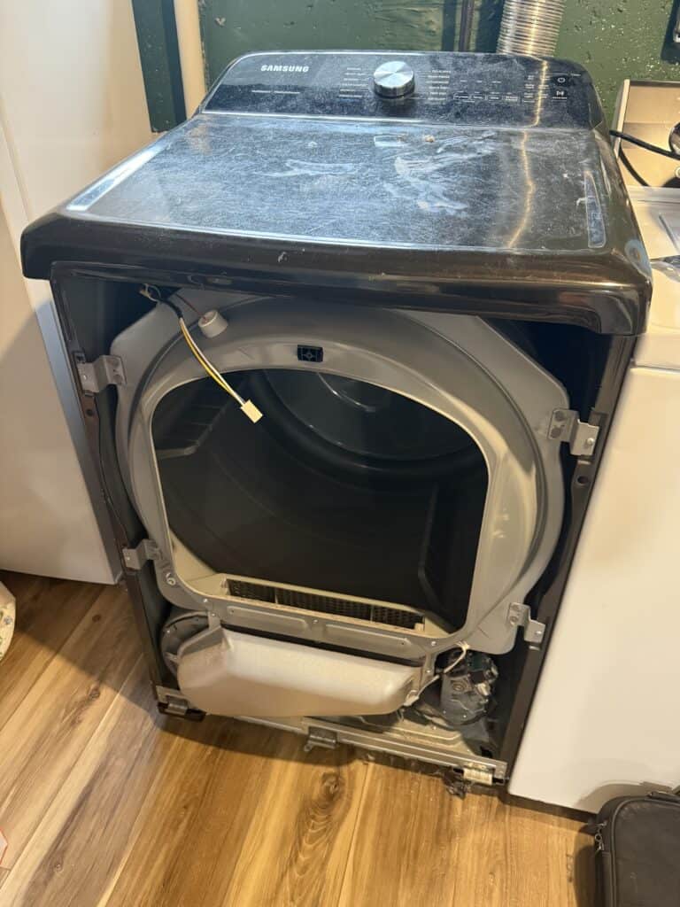 Partially disassembled dryer machine showing internal drum and wiring, used to diagnose slow drying performance issues.