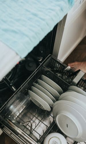 Open dishwasher with clean dishes used to illustrate troubleshooting when the dishwasher isn't cleaning dishes properly