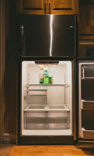 Empty refrigerator with a few drinks and shelves exposed—visual cue for homeowners wondering, Is your fridge running efficiently?