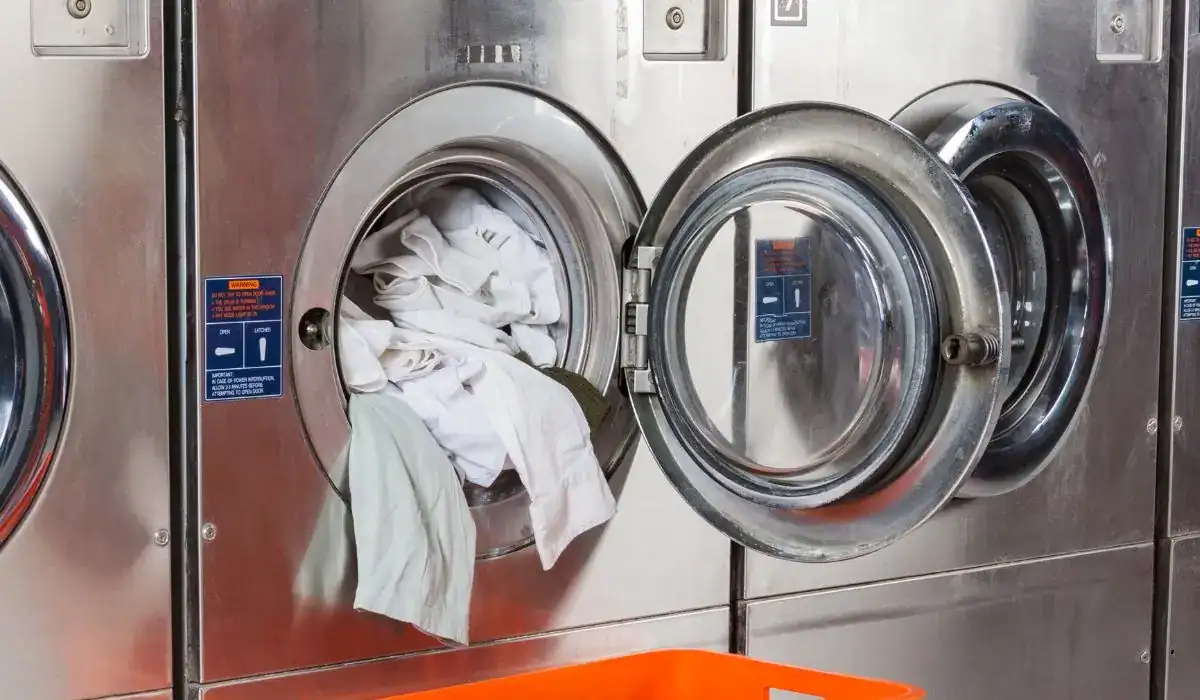 Open front-load dryer with overstuffed laundry, illustrating airflow restriction and potential dryer vent blockage risks.