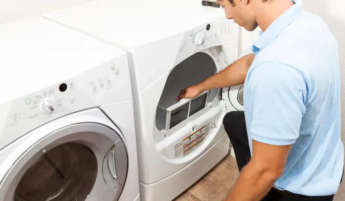 Man cleaning a dryer lint trap to help prevent clogged dryer vent issues and reduce fire risks in a residential laundry room.