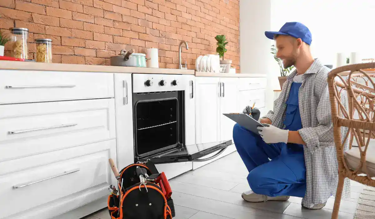Technician inspecting kitchen oven as part of a fall appliance maintenance checklist in a residential home.