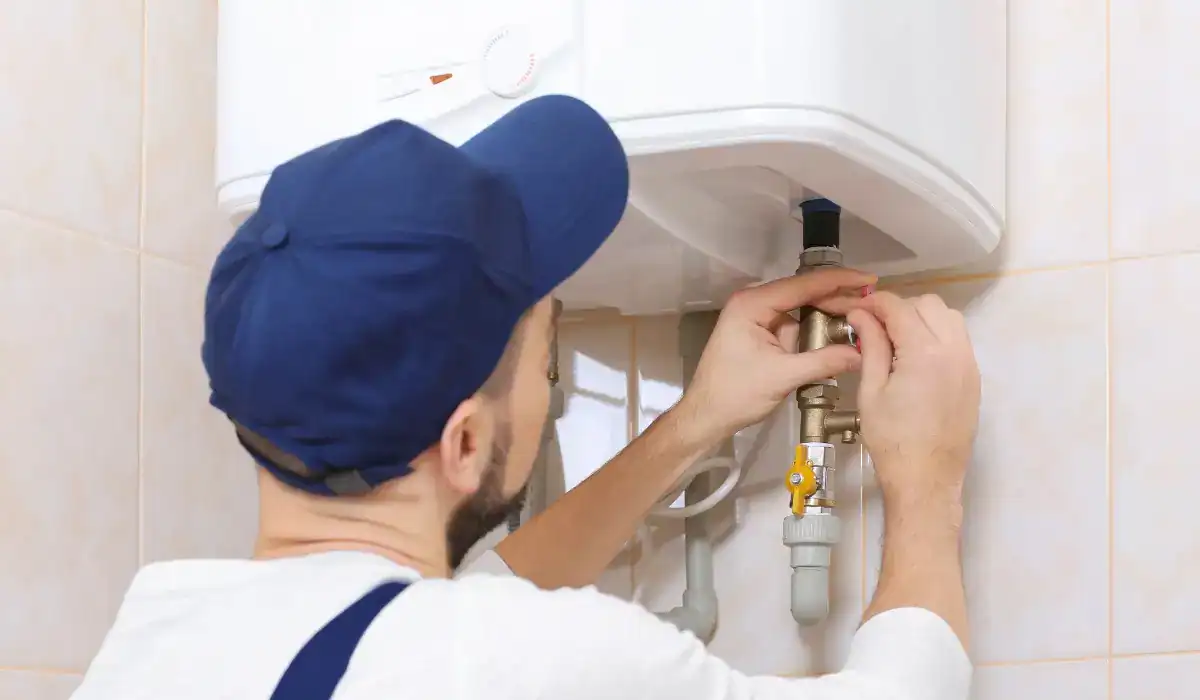 Technician inspecting and adjusting a home water heater as part of a fall maintenance checklist to ensure safe and efficient appliance operation.